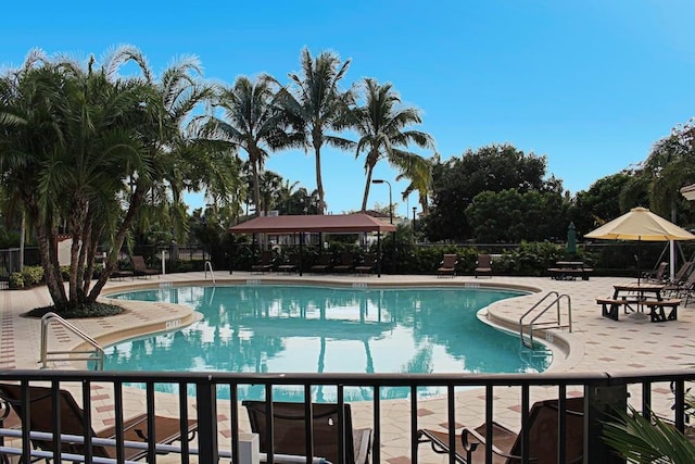 community pool with a patio area and fence