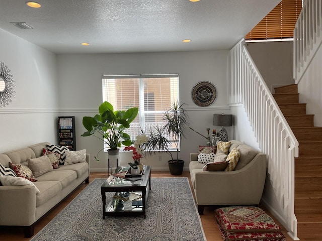 living area with stairs, wood finished floors, visible vents, and a textured ceiling