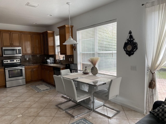 kitchen featuring dark countertops, visible vents, light tile patterned floors, decorative backsplash, and stainless steel appliances