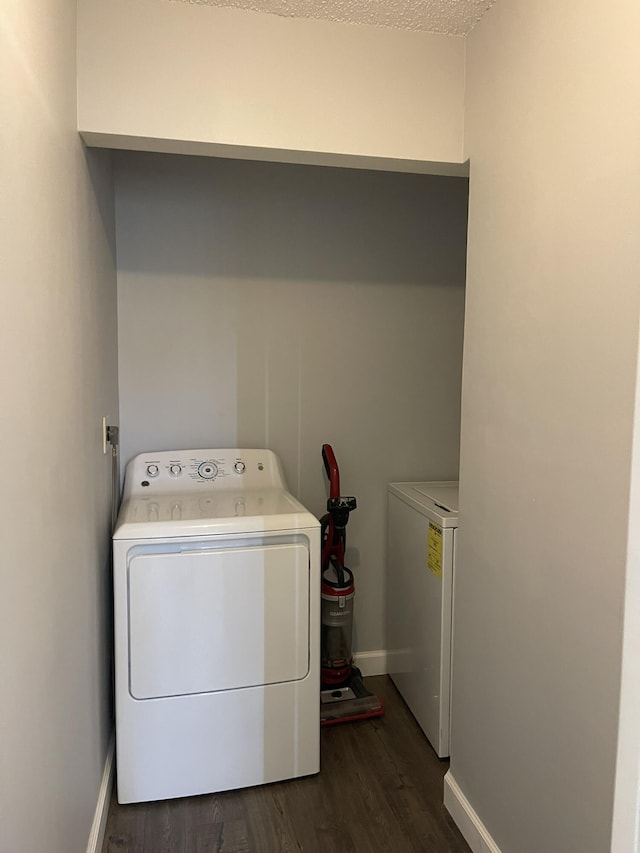 laundry room with dark wood-style floors, laundry area, washer and dryer, and baseboards