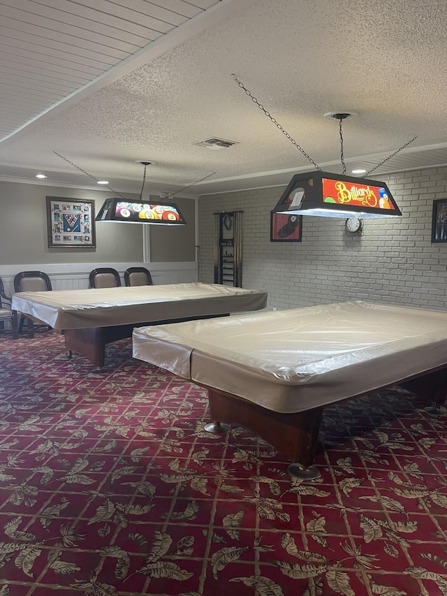 recreation room featuring billiards, carpet, visible vents, brick wall, and a textured ceiling