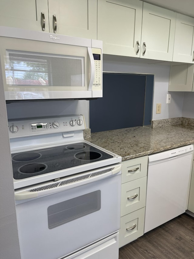 kitchen with dark wood-style floors, stone counters, white cabinets, and white appliances