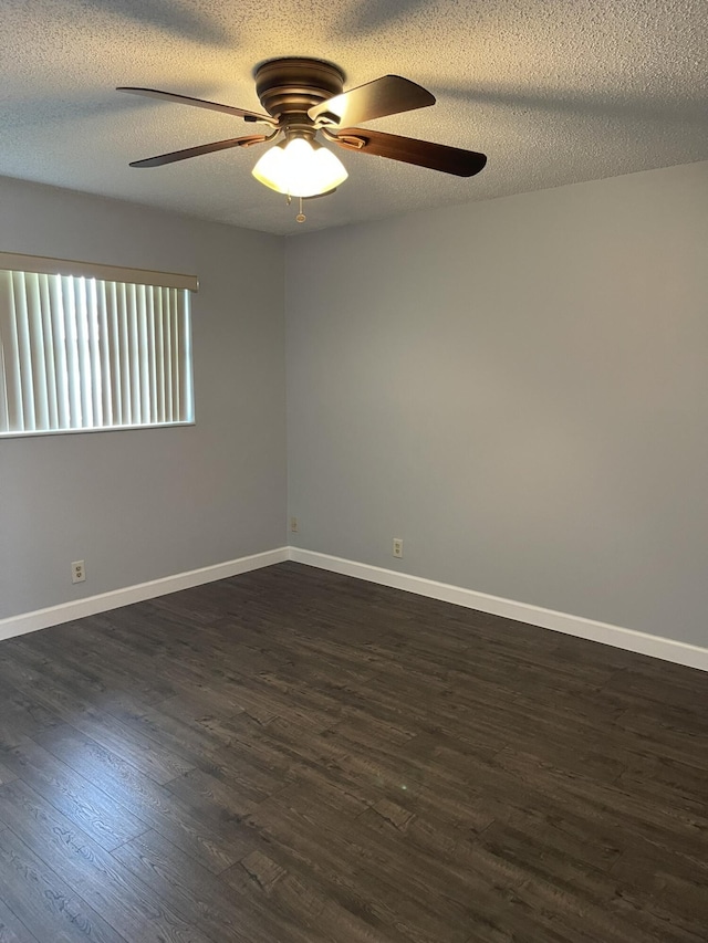 unfurnished room with baseboards, a textured ceiling, dark wood-style floors, and a ceiling fan