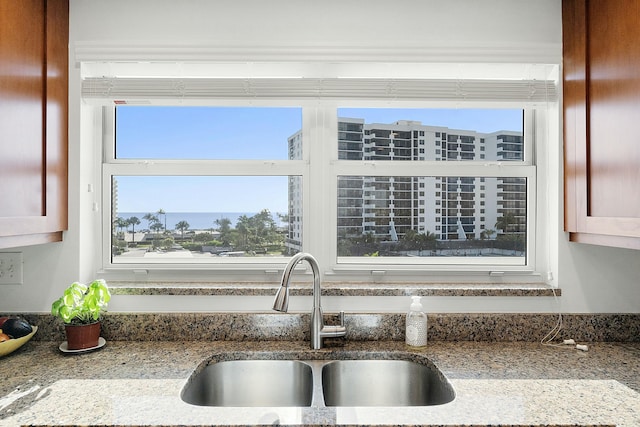 room details with light stone countertops and a sink