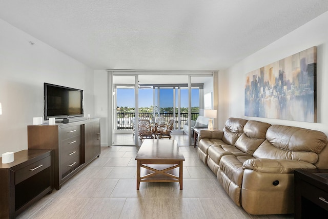 living area with light tile patterned flooring, a textured ceiling, and a wall of windows