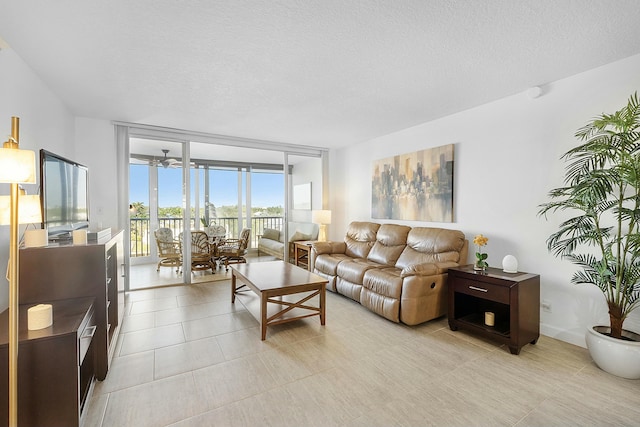 living room with light tile patterned floors, a textured ceiling, a wall of windows, and a ceiling fan