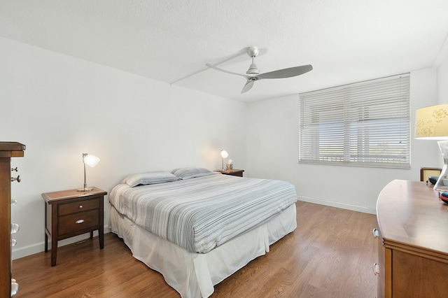 bedroom with a ceiling fan, wood finished floors, and baseboards