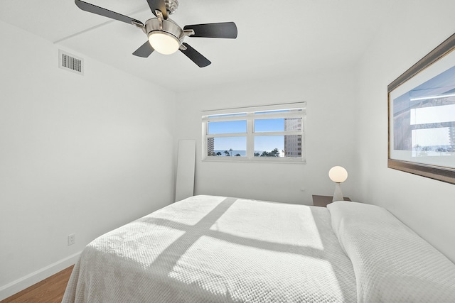 bedroom featuring visible vents, multiple windows, baseboards, and wood finished floors