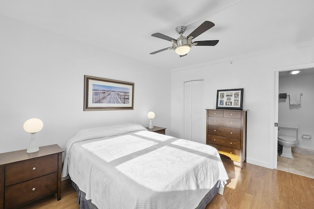 bedroom with connected bathroom, a closet, wood finished floors, and ceiling fan