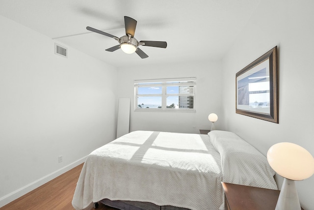 bedroom with visible vents, baseboards, wood finished floors, and a ceiling fan