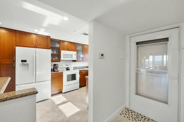 kitchen featuring white appliances, glass insert cabinets, brown cabinetry, and visible vents