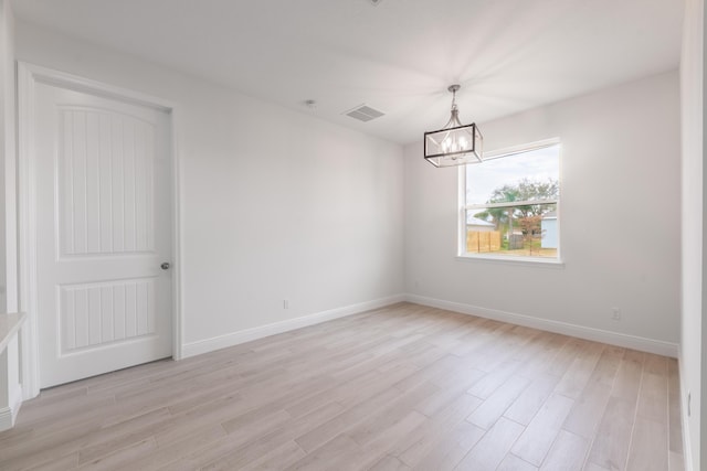 unfurnished room featuring a chandelier, visible vents, baseboards, and light wood-style floors