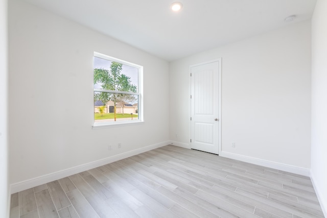 spare room featuring light wood-style flooring, recessed lighting, and baseboards