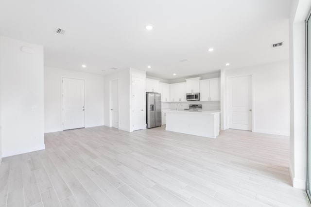 unfurnished living room featuring light wood finished floors, visible vents, recessed lighting, and a sink