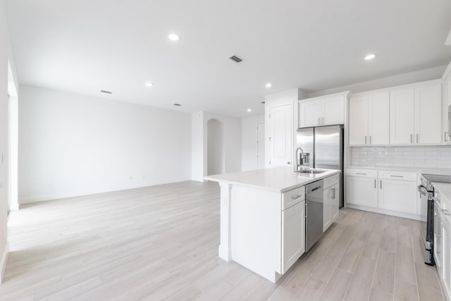 kitchen featuring visible vents, a sink, stainless steel appliances, light countertops, and decorative backsplash