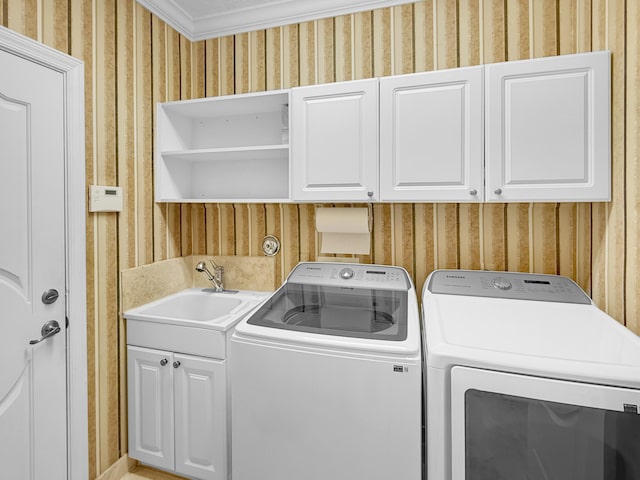 clothes washing area featuring cabinet space, wallpapered walls, independent washer and dryer, and a sink