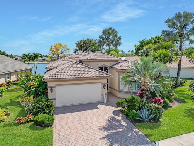 mediterranean / spanish-style house featuring stucco siding, a tile roof, decorative driveway, a front yard, and an attached garage