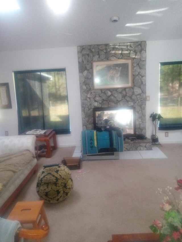 carpeted living area featuring a stone fireplace