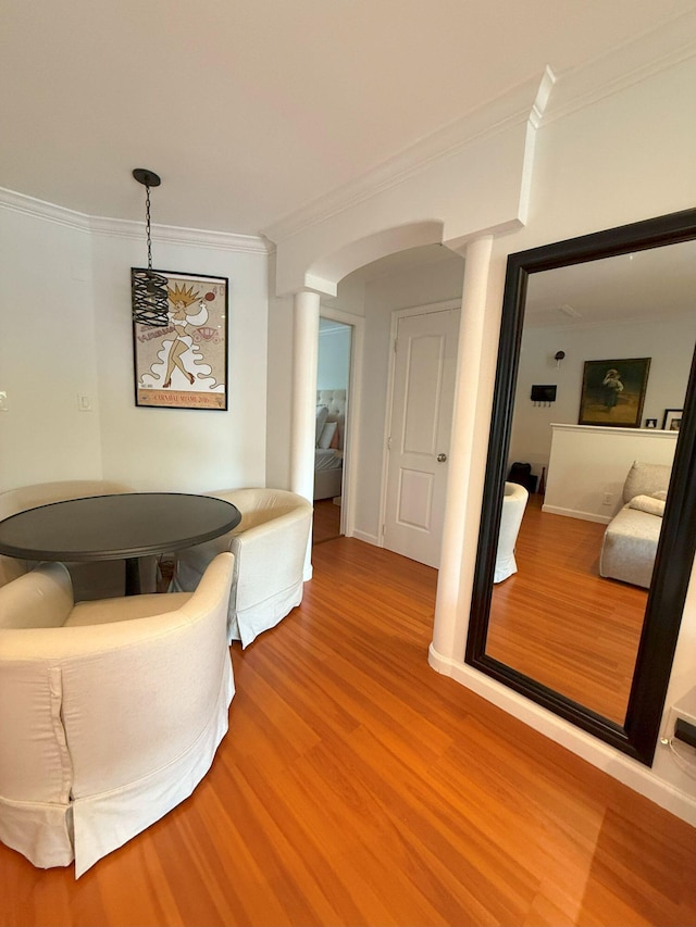 interior space featuring wood finished floors, baseboards, decorative columns, arched walkways, and crown molding