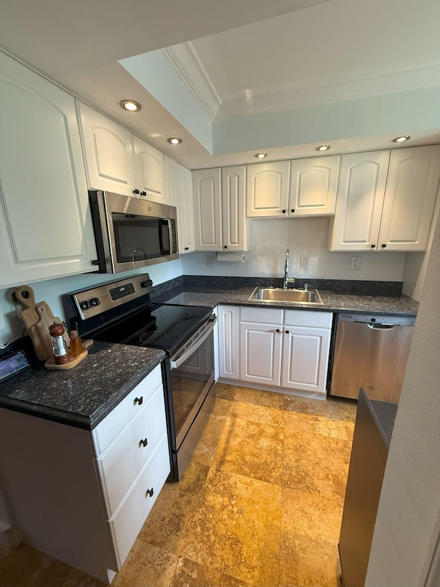 kitchen featuring white cabinetry, stainless steel appliances, a tray ceiling, and a sink