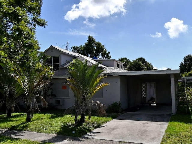 view of front of property featuring stucco siding, a front yard, a carport, and driveway