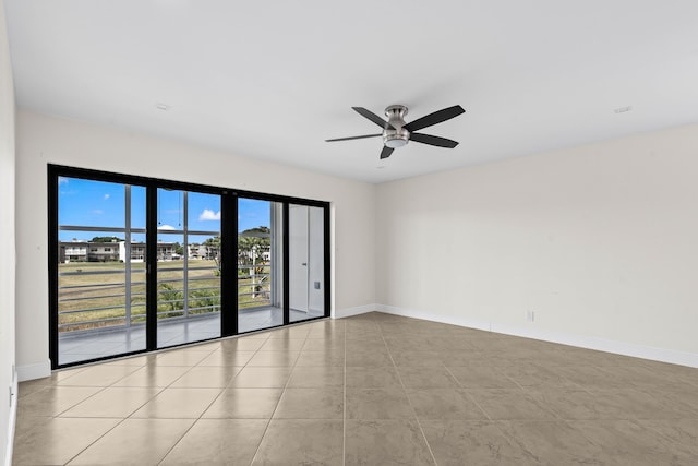 tiled empty room featuring baseboards and ceiling fan