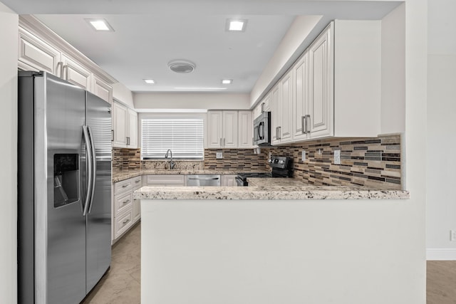 kitchen featuring light stone counters, a peninsula, decorative backsplash, appliances with stainless steel finishes, and white cabinetry