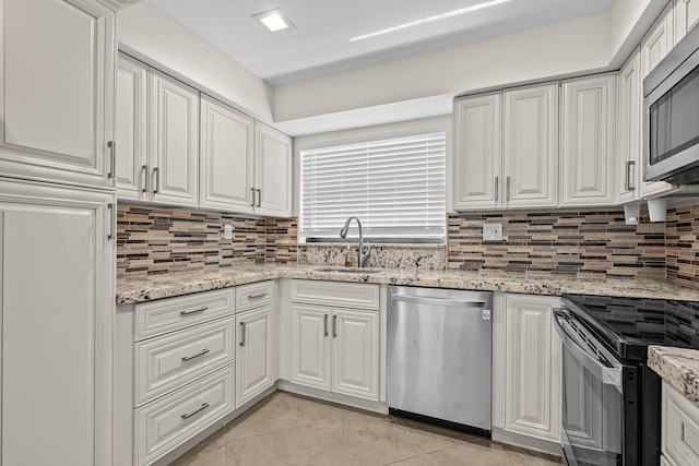 kitchen with a sink, decorative backsplash, white cabinets, and stainless steel appliances