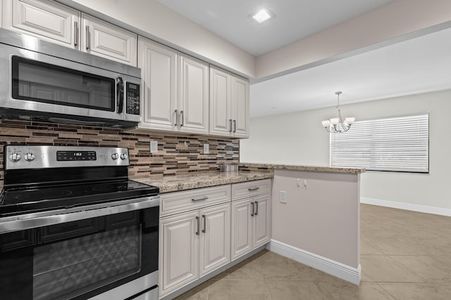 kitchen featuring light stone countertops, decorative backsplash, appliances with stainless steel finishes, white cabinetry, and a notable chandelier