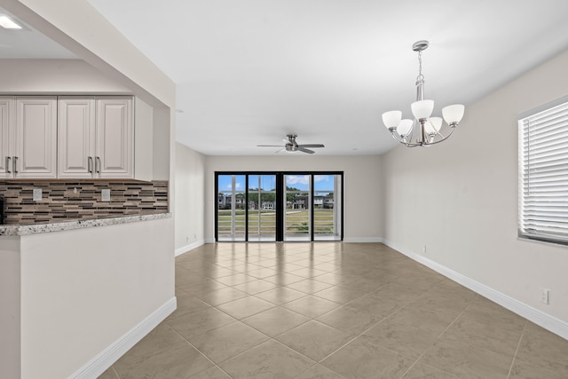 interior space with light tile patterned flooring, ceiling fan with notable chandelier, and baseboards