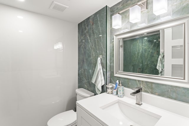 bathroom with vanity, tile walls, toilet, and visible vents