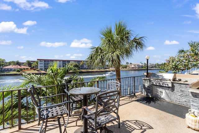 view of patio featuring a water view, a balcony, area for grilling, and exterior kitchen