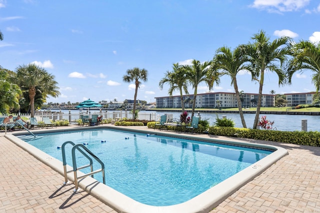 community pool with a patio area, a water view, and fence