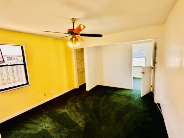 carpeted empty room with baseboards and a ceiling fan