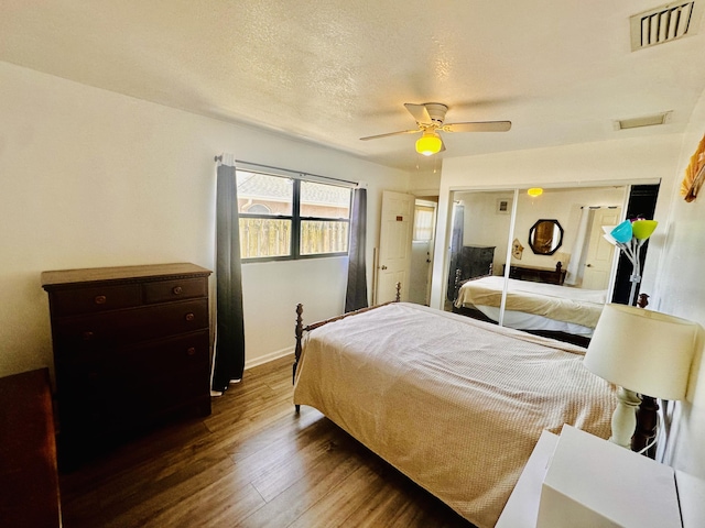 bedroom featuring visible vents, a textured ceiling, dark wood finished floors, and a ceiling fan