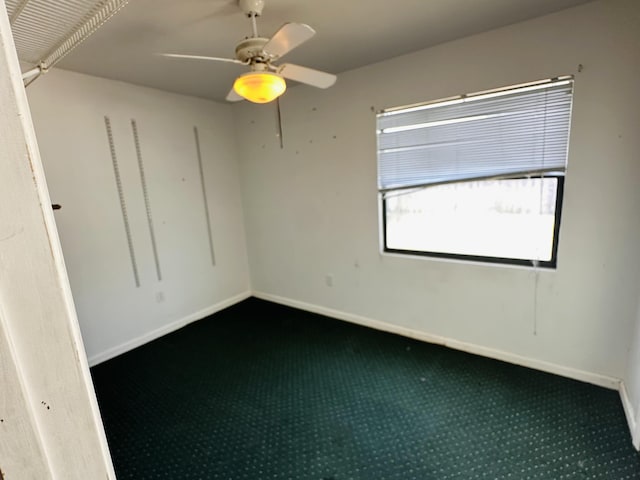 carpeted spare room with a ceiling fan and baseboards