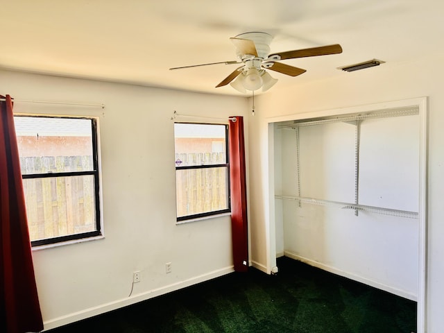 unfurnished bedroom featuring baseboards, multiple windows, a closet, and dark colored carpet