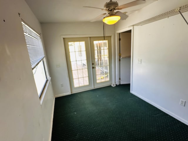 unfurnished room featuring baseboards, plenty of natural light, and dark colored carpet