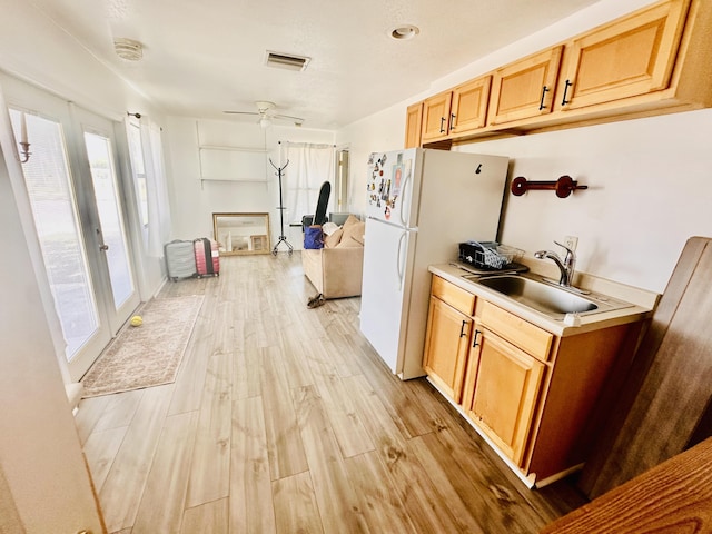 kitchen featuring a sink, light wood finished floors, light countertops, freestanding refrigerator, and visible vents