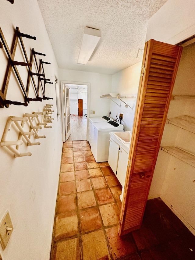 laundry room with a textured ceiling, cabinet space, and washing machine and dryer