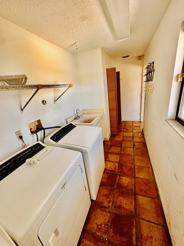 washroom featuring laundry area, a sink, a textured ceiling, and washing machine and dryer