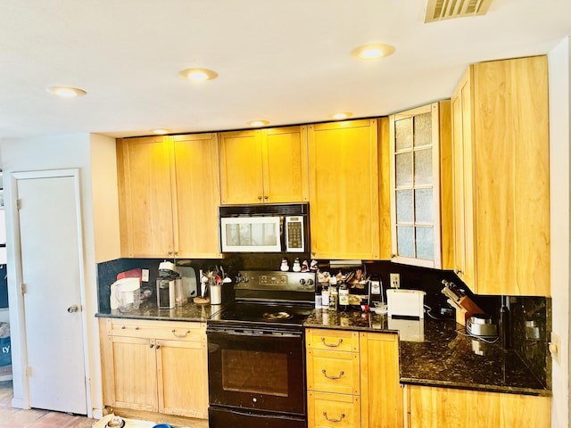 kitchen featuring visible vents, black range with electric stovetop, light brown cabinetry, dark stone countertops, and white microwave