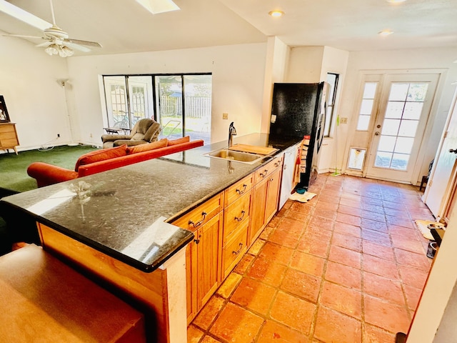 kitchen with freestanding refrigerator, a peninsula, recessed lighting, brown cabinets, and a sink