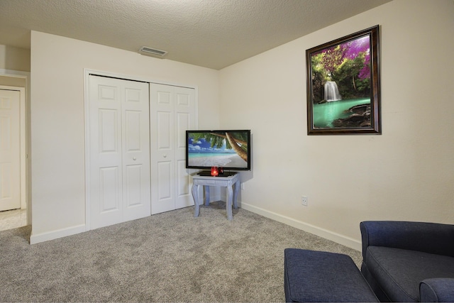 sitting room with visible vents, baseboards, carpet, and a textured ceiling