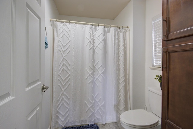 bathroom with a shower with shower curtain and toilet