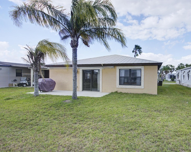 rear view of house with stucco siding, a patio, and a yard