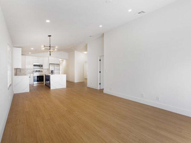 4524 Concordia Ln, Boynton Beach, FL 33436 - unfurnished living room featuring a chandelier, vaulted ceiling, recessed lighting, and light wood-type flooring