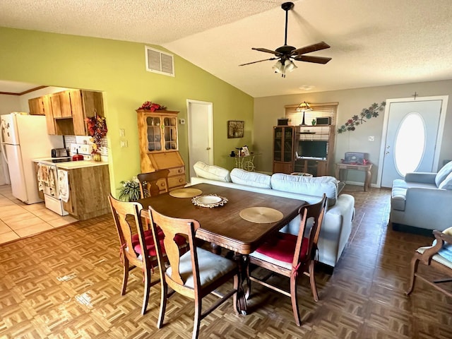 dining area featuring vaulted ceiling, a ceiling fan, visible vents, and a textured ceiling