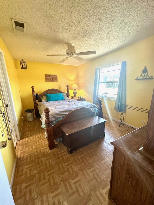 bedroom with visible vents, baseboards, a textured ceiling, and a ceiling fan