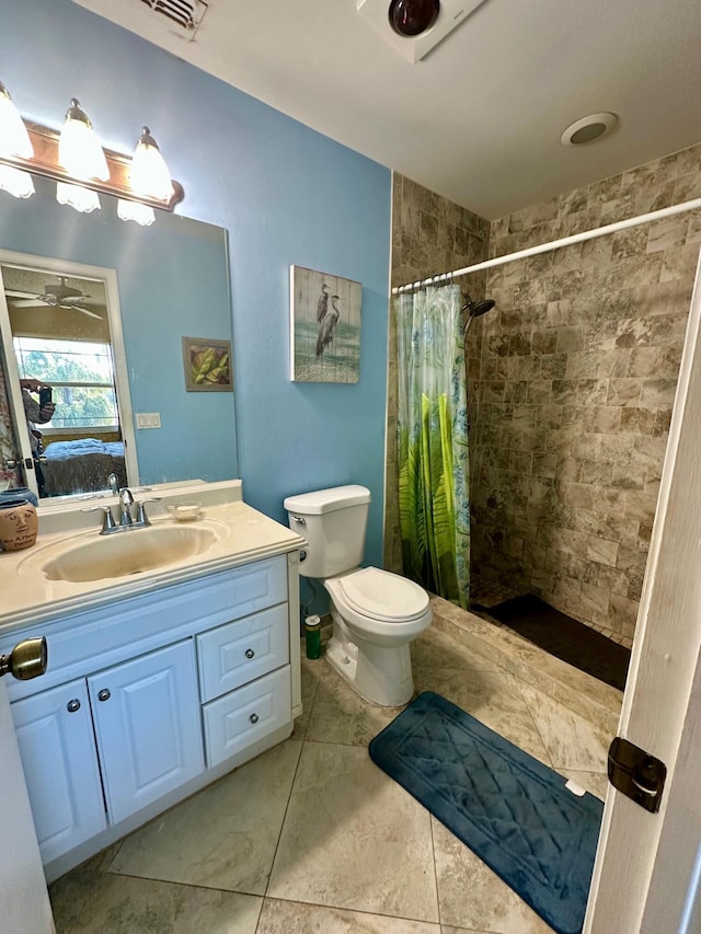 bathroom featuring visible vents, toilet, tiled shower, vanity, and a ceiling fan